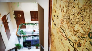 A hallway with a wooden railing, a staircase, and a potted plant. - Casa Nautilus Cadiz (Cádiz)