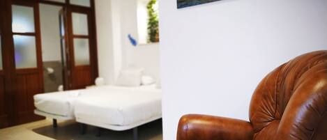 A room with a bed, a brown leather chair, and a painting on the wall.