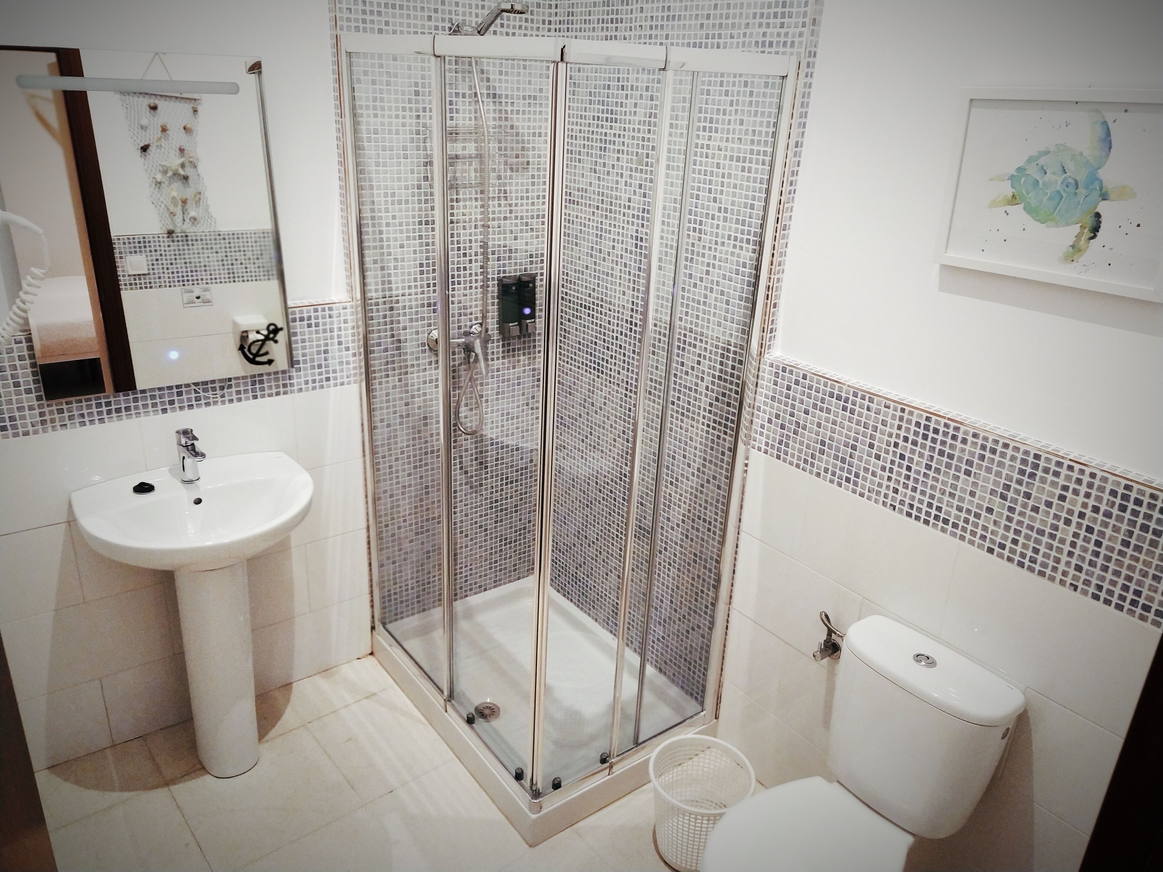 Une salle de bain avec une douche à parois de verre, un lavabo et des toilettes.