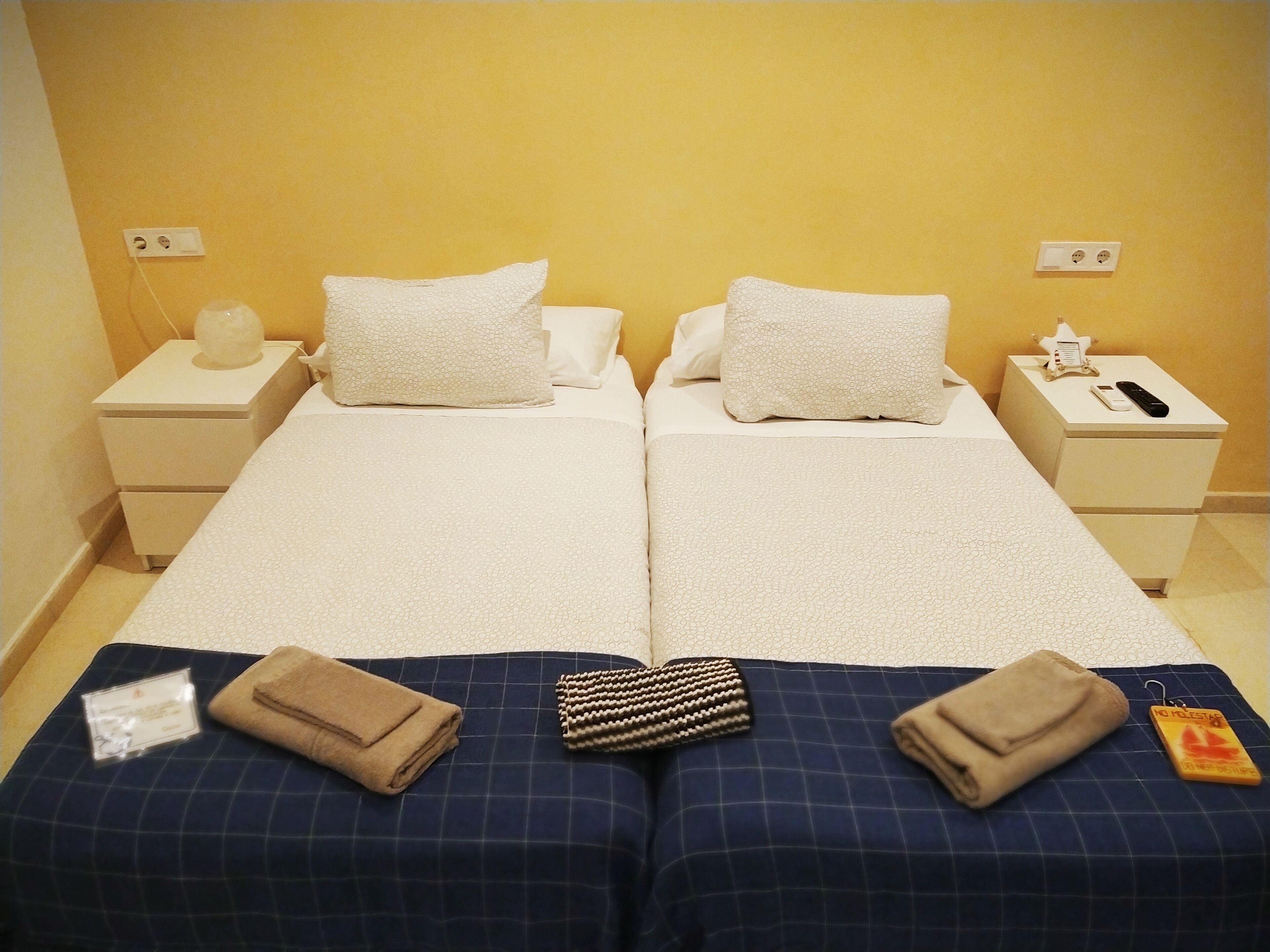 A double bed with white linens, two bedside tables with lamps, and a small bedside table with a phone and a tissue box.