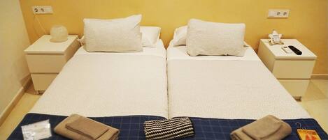 A double bed with white linens, two bedside tables with lamps, and a small bedside table with a phone and a tissue box.