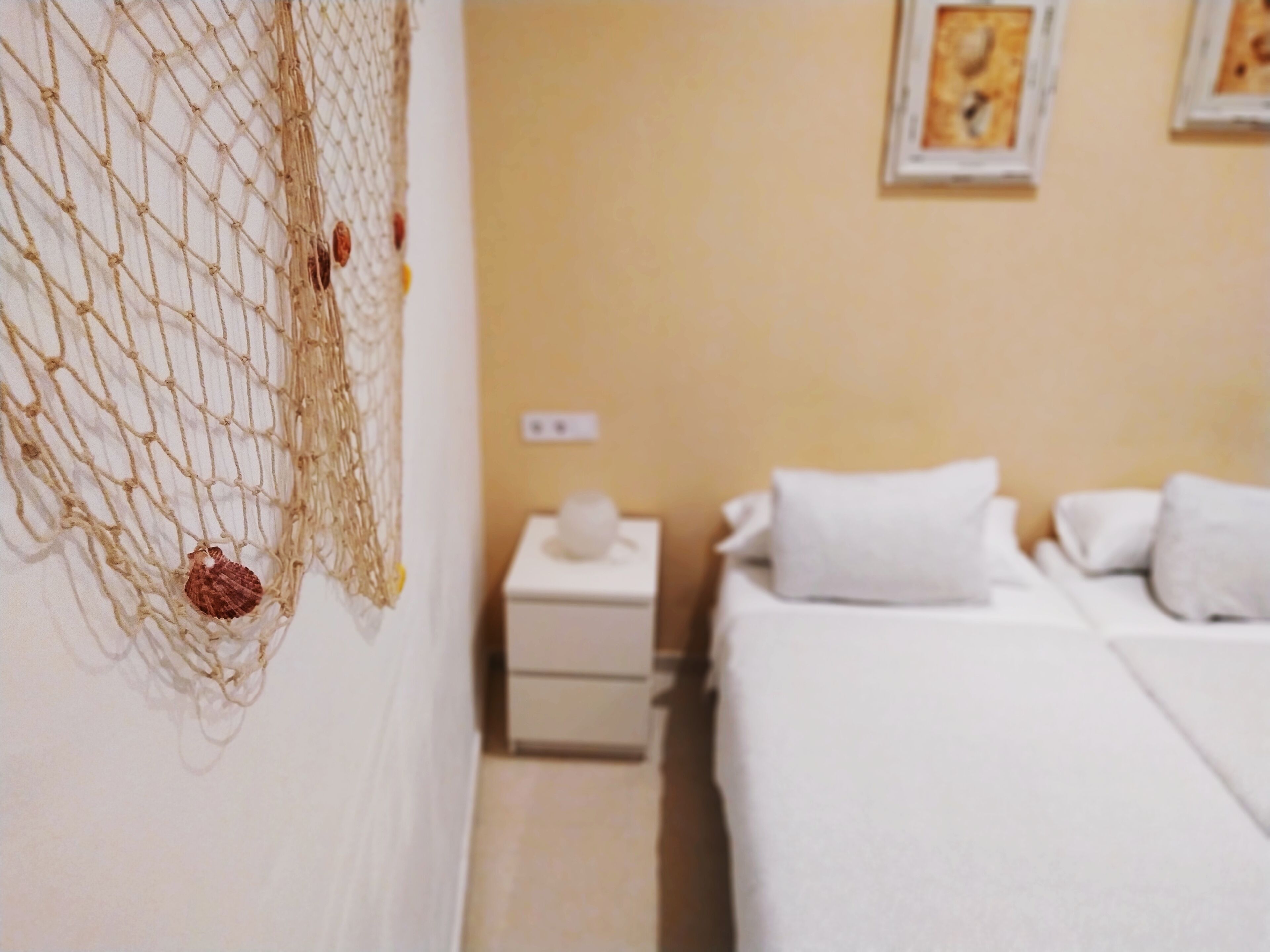 Una habitación de hotel con una cama, una mesita de noche y un cuadro en la pared.