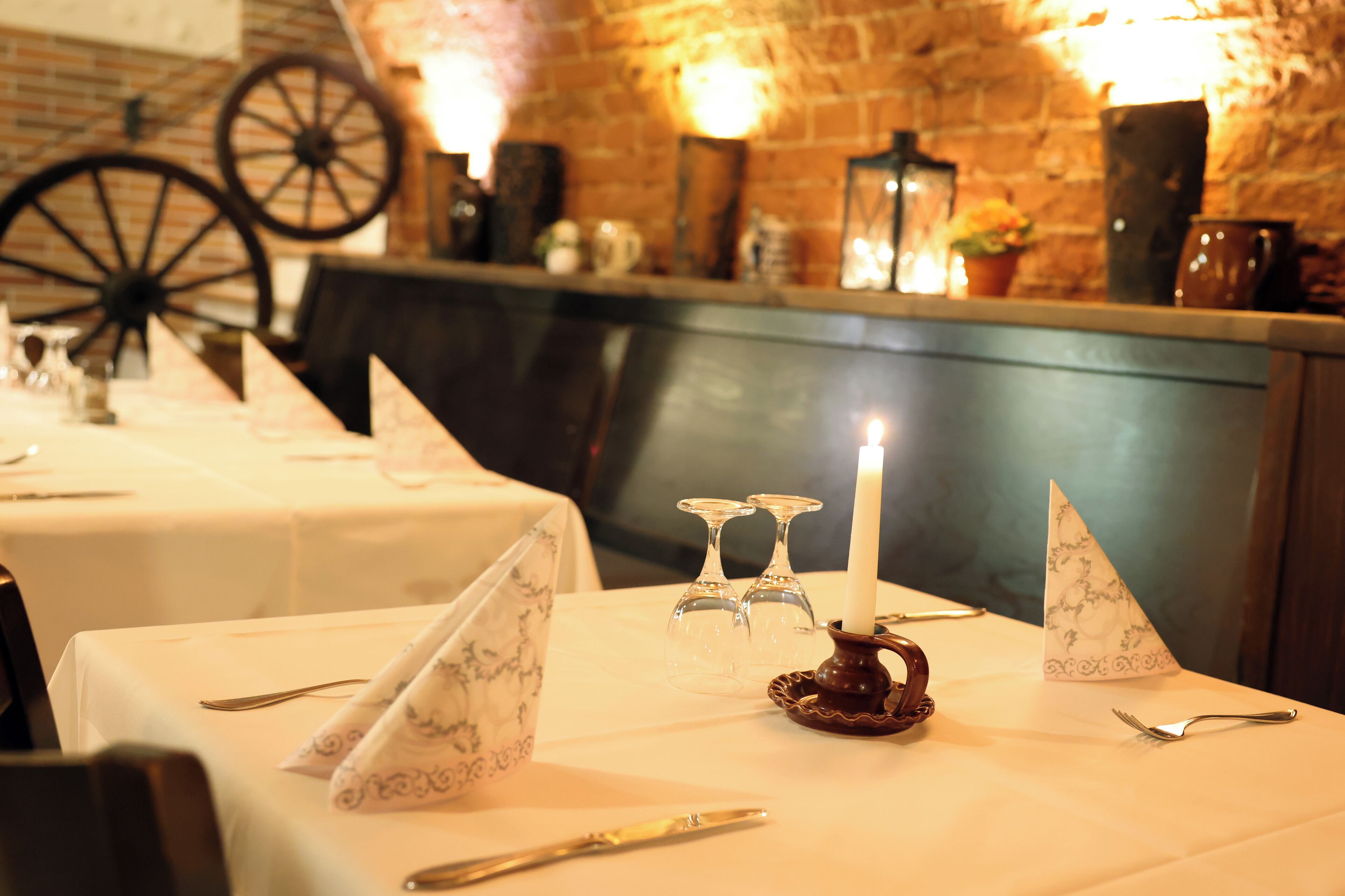 A dining table set with a candle, wine glasses, and a decorative napkin holder.