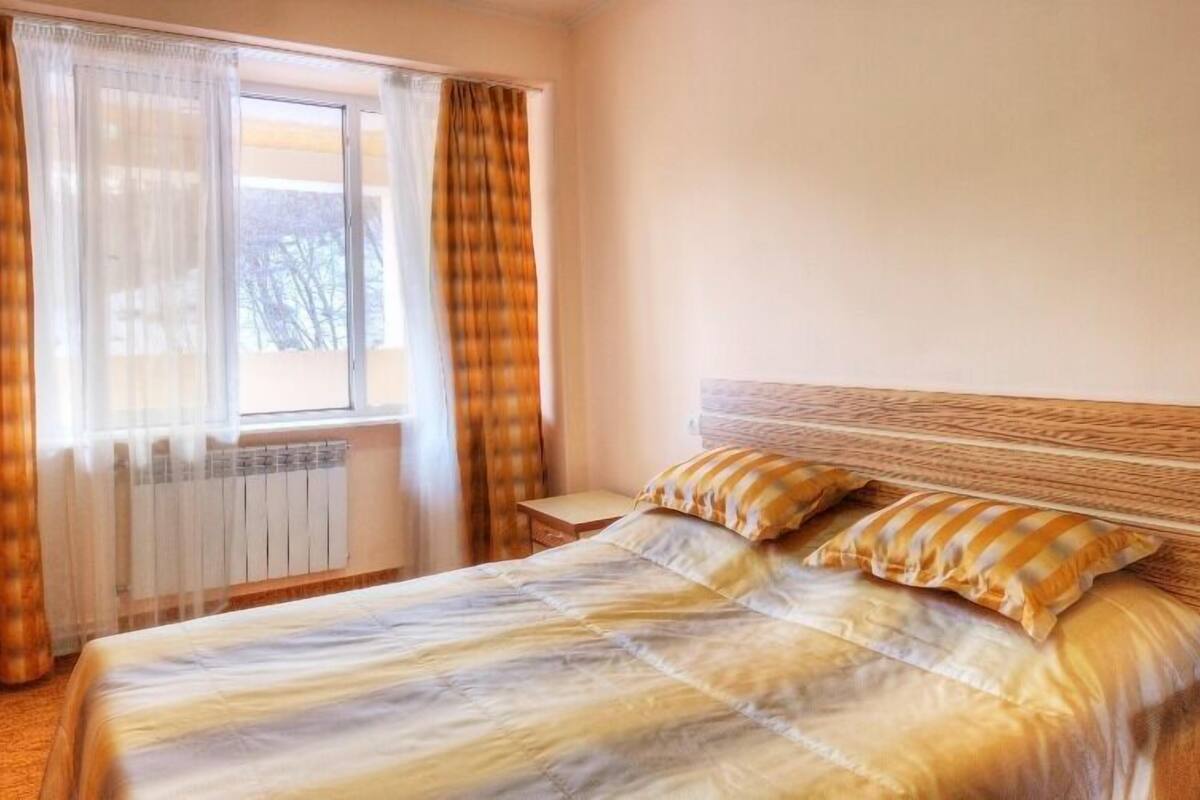 A bedroom with a bed, curtains, and a radiator.