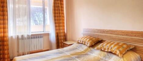 Quarto com cama, cortinas e radiador.