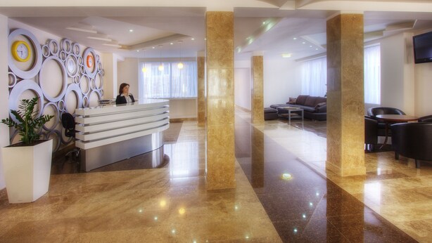 A modern hotel lobby with a reception desk, seating area, and a large TV screen. - Tsaghkahovit (Tsaghkadzor)