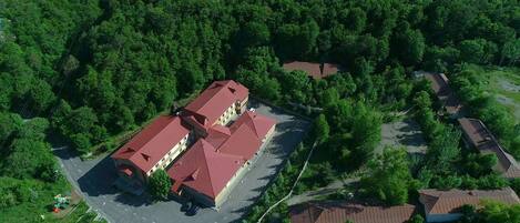 An aerial view of a building complex surrounded by dense forest.