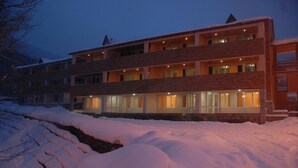 A multi-story hotel with a stone facade, large windows, and a snow-covered landscape. - Tsaghkahovit (Tsaghkadzor)