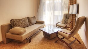 A living room with a sofa, armchair, coffee table, and a flat-screen TV mounted on the wall. - Tsaghkahovit (Tsaghkadzor)