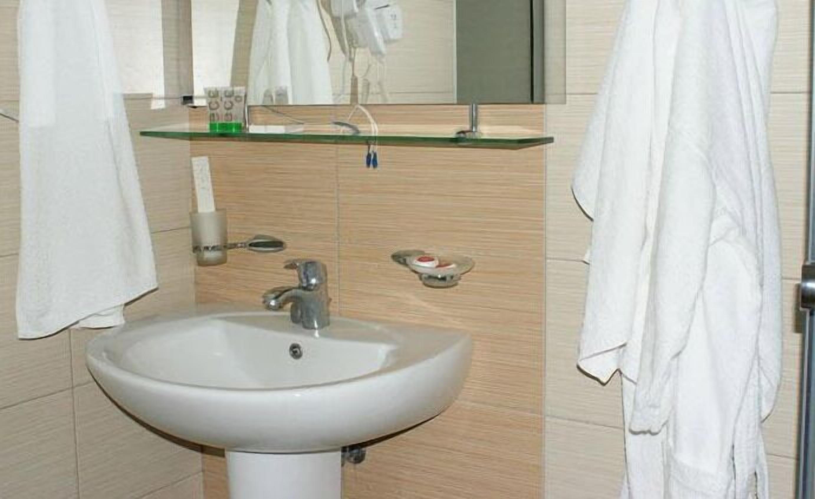 A bathroom with a white sink, a mirror, and a towel rack.
