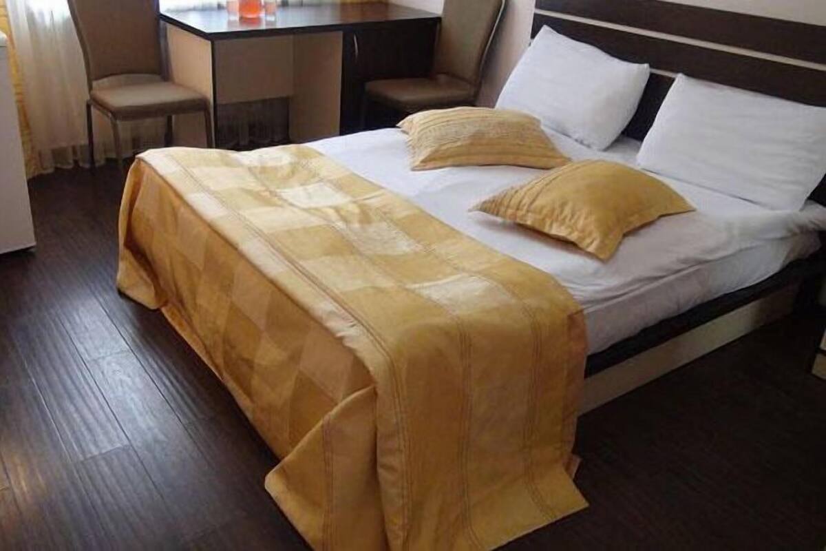 A hotel room with a bed, a desk, and a chair.