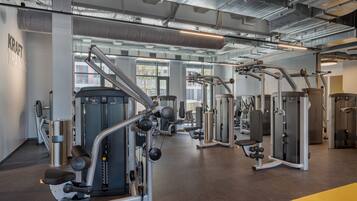 A gym with various exercise machines, large windows, and a clean, modern design.