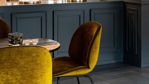 A modern kitchen with a dark blue cabinet, a yellow chair, and a stainless steel refrigerator.