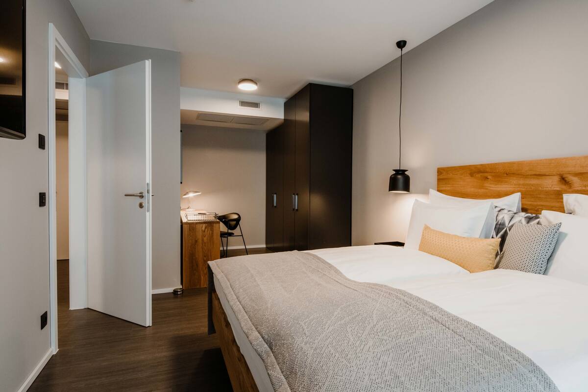 Un dormitorio moderno con una cama grande, un cabecero de madera y un escritorio con una silla.