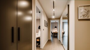 A modern hallway with a wooden floor, a dining area with a table and chairs, and a framed map on the wall.