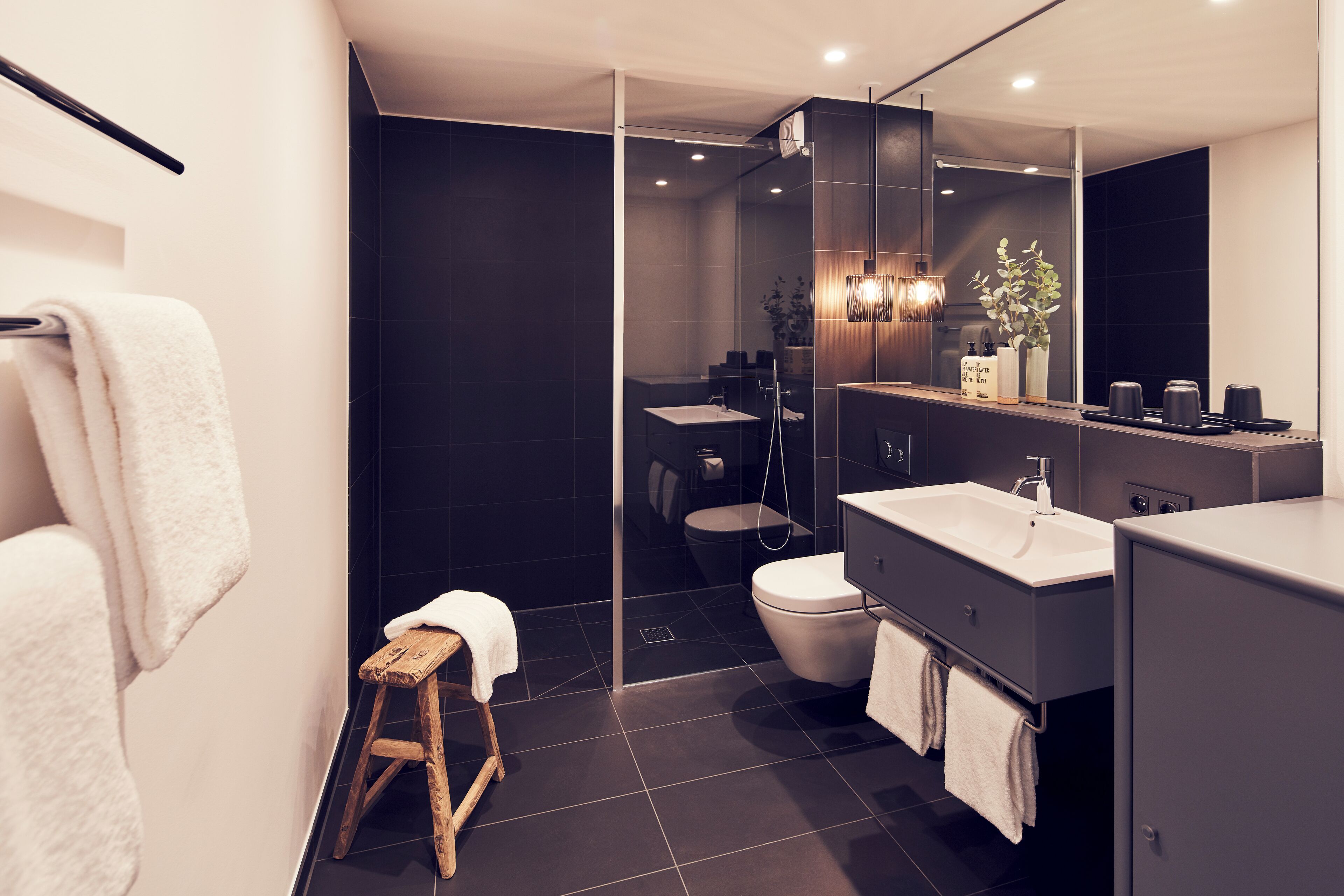 A modern bathroom with a glass shower enclosure, a white sink, and a dark-toned vanity.