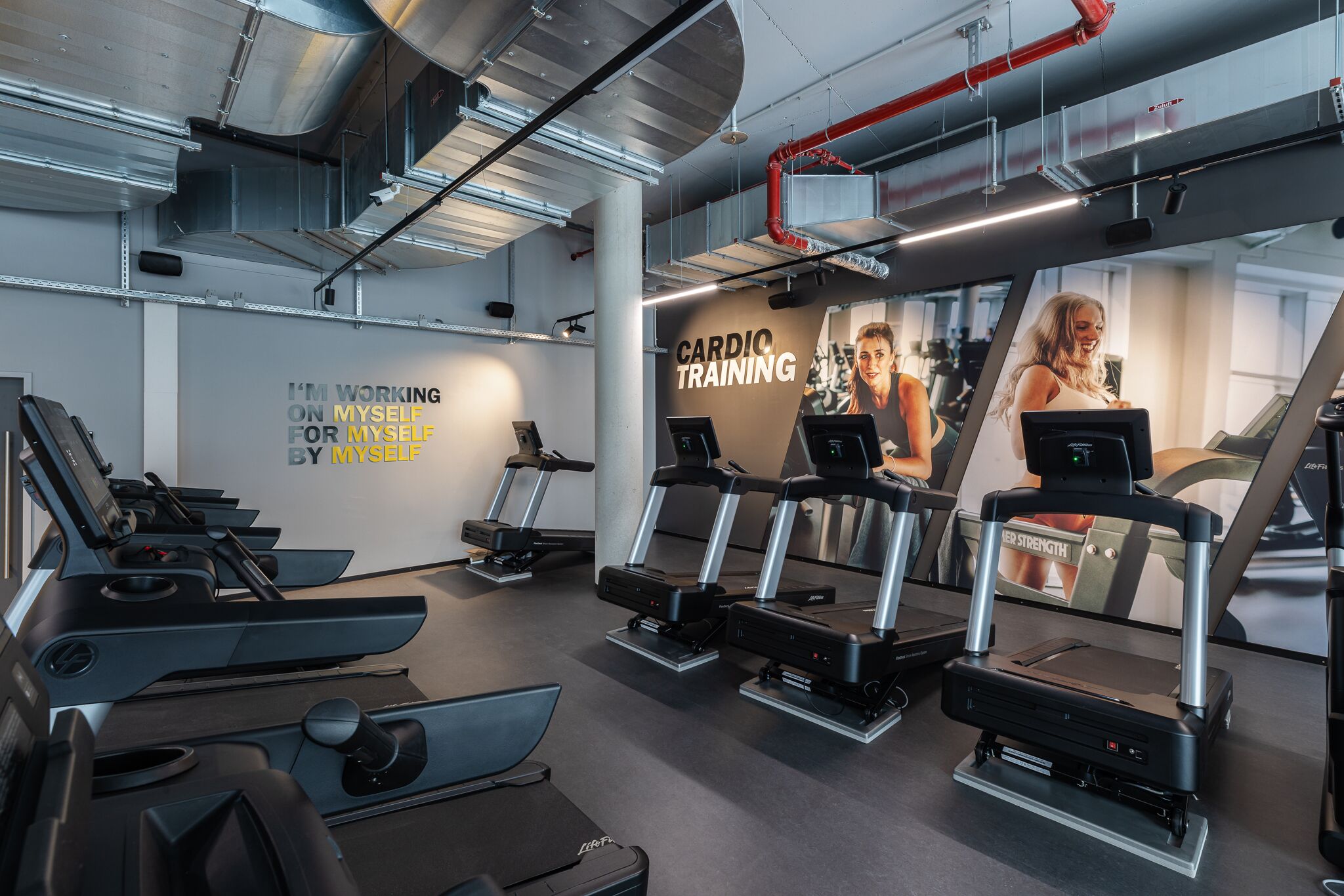A gym with treadmills, stationary bikes, and a wall with motivational text.