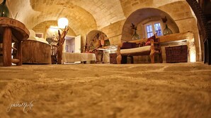A rustic interior with stone arches, wooden furniture, and a warm light source. - Domus Decclesiis (Gravina in Puglia)