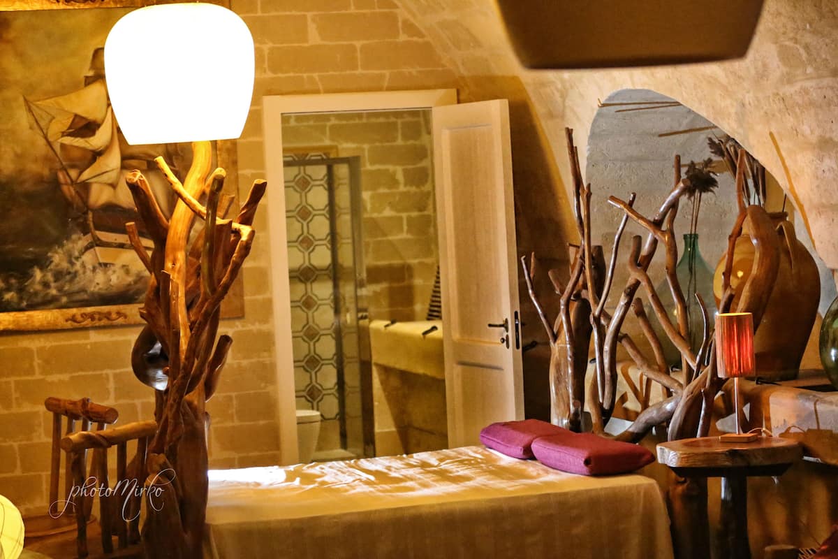 A rustic room with wooden decor, a bed with a white bedspread, and a small table with a lamp.