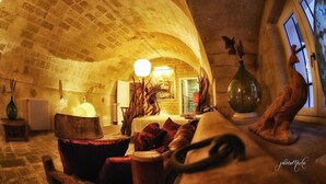 A cozy, rustic interior with exposed brick walls, a wooden bench, and a large vase. - Domus Decclesiis (Gravina in Puglia)