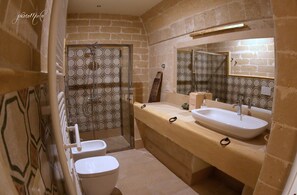 A bathroom with a shower, toilet, and sink, featuring a tiled wall and a large mirror. - Domus Decclesiis (Gravina in Puglia)