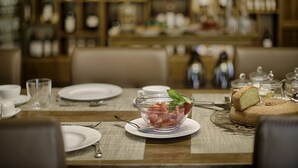 A dining table set with plates, glasses, and a bowl of food, with a wooden backdrop and shelves in the background. - Luxury Chianti in Olives in Panzano Chianti (Panzano)