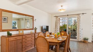 A dining area with a wooden table, wicker chairs, and a large mirror above. - Apartment Arenal 4 - PlusHolidays (Calpe)