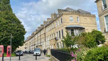 A row of traditional terraced houses with a central bay window, a red telephone booth, and parked cars on the street.