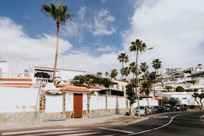 A residential street with white houses, palm trees, and parked cars. - Endless Summer Hostel - Adults Only (Adeje)