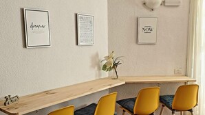 Un comedor con una mesa de madera y cuatro sillas amarillas. Hay tres frases inspiradoras enmarcadas en la pared.