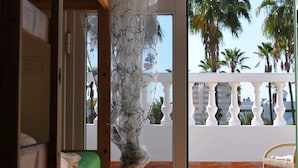Una habitación con una cama nido de madera, un colchón verde y una cortina blanca con un diseño de árbol.