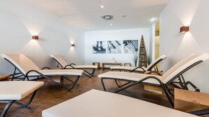A room with four lounge chairs, a wooden bench, and a wall-mounted projector.