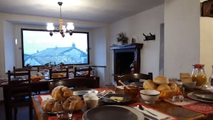 A dining area with a table set for breakfast, including croissants, bread, and a bottle of orange juice. - B&B Rocca di Bajedo (Pasturo)