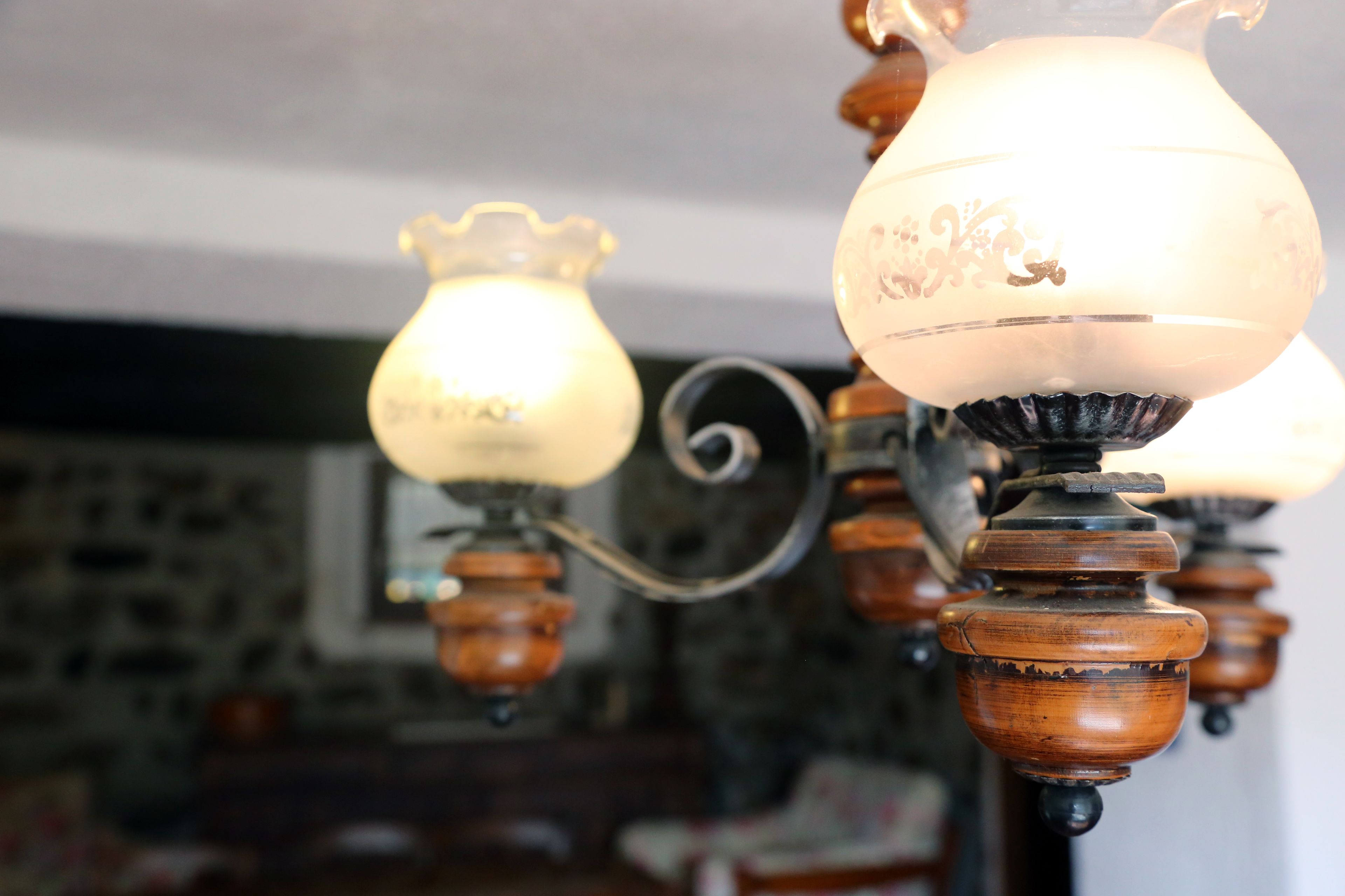 Gros plan d’un lustre orné, doté d’abat-jours en forme de bougies et de détails en bois.