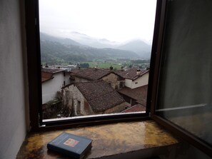 A view from a window overlooking a town with traditional buildings and mountains in the background. - B&B Rocca di Bajedo (Pasturo)