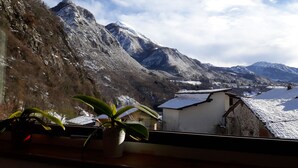 A mountainous landscape with snow-covered peaks and a village below. - B&B Rocca di Bajedo (Pasturo)
