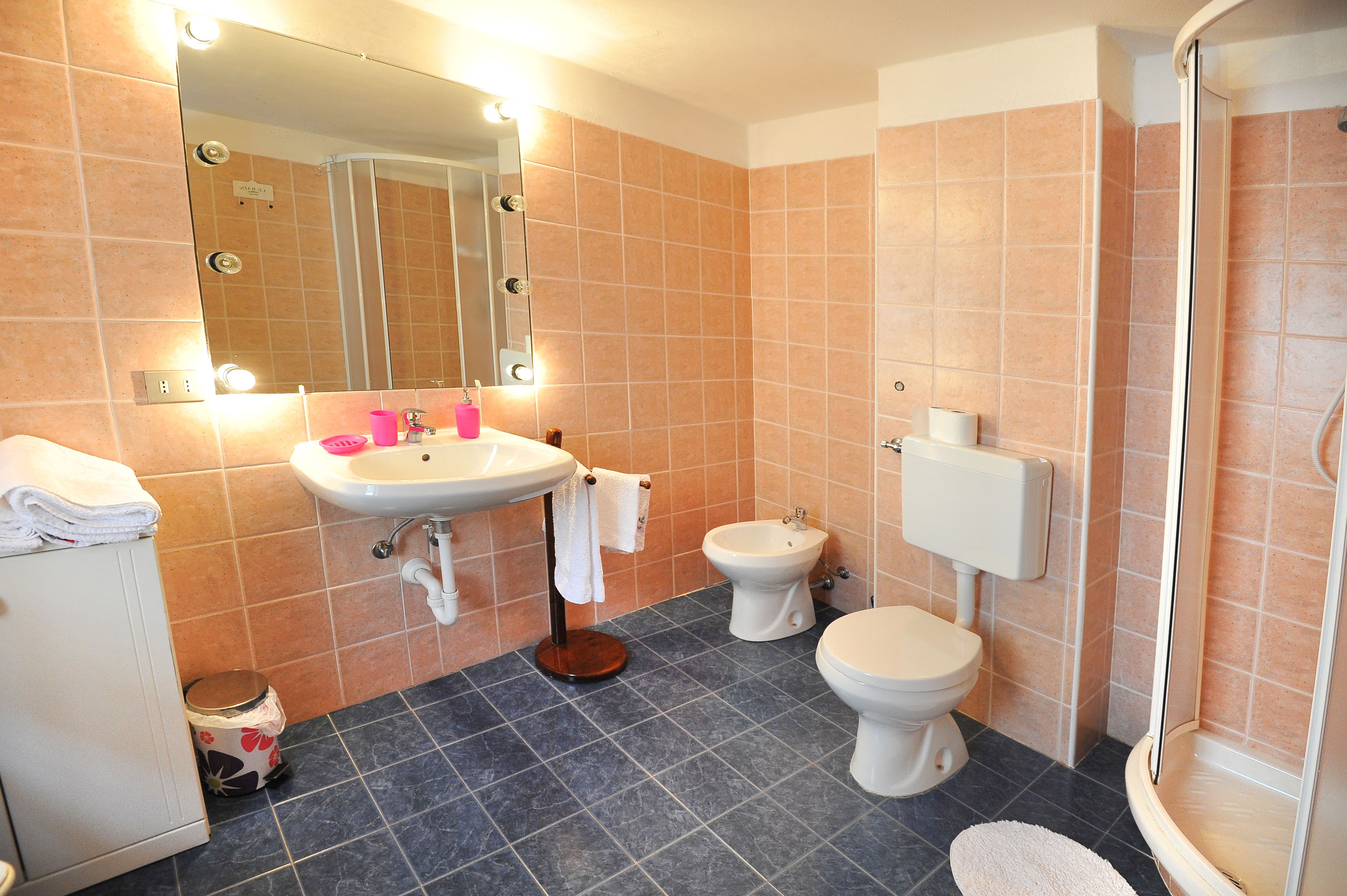 A bathroom with a sink, bidet, toilet, and a shower area.