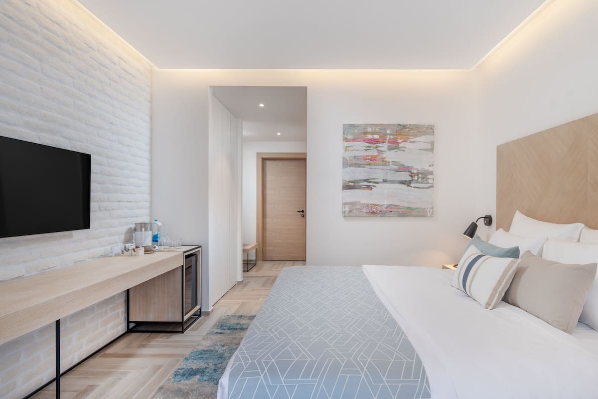 Ein modernes Hotelzimmer mit einem großen Bett, einem flachbildfernseher an einer Ziegelwand, einem Nachttisch aus Holz und einem Gemälde an der Wand.