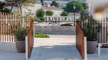 Un sendero pavimentado que conduce a un edificio con un muro de piedra y plantas en macetas.