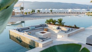 Un espace aménagé au bord de la piscine, avec un mobilier contemporain, une vue sur la plage et des parasols.