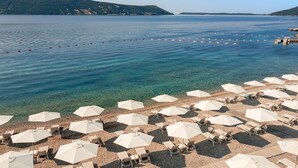 Une plage avec une eau claire, des parasols et des chaises longues.