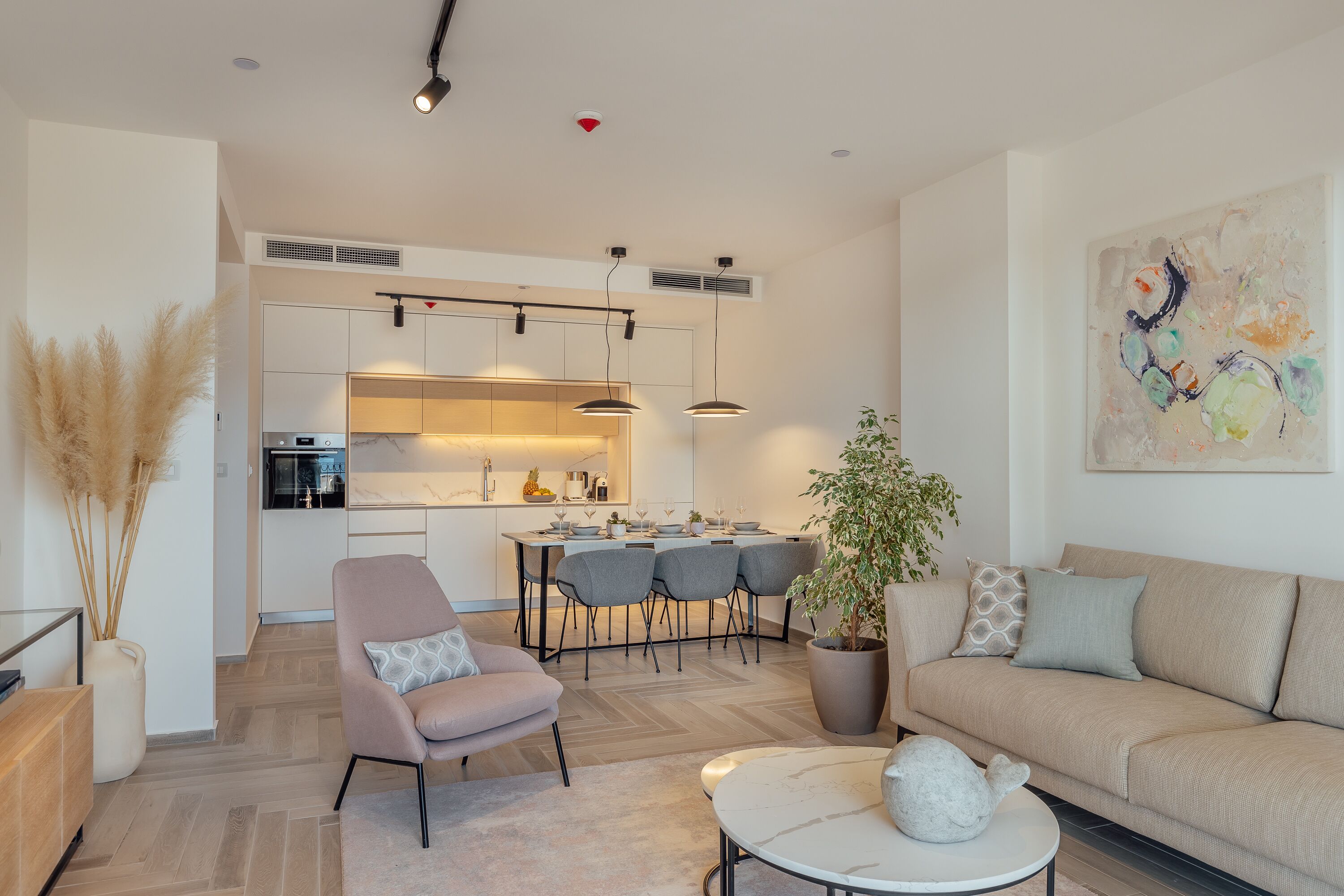 A modern living room with a sofa, a coffee table, and a dining area with chairs and a table.