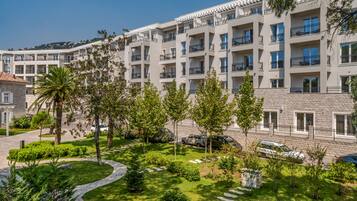 A multi-story hotel with balconies, a landscaped garden, and a stone facade.