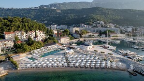 Un port de plaisance situé sur la côte, avec des bateaux, une piscine et des parasols de plage.