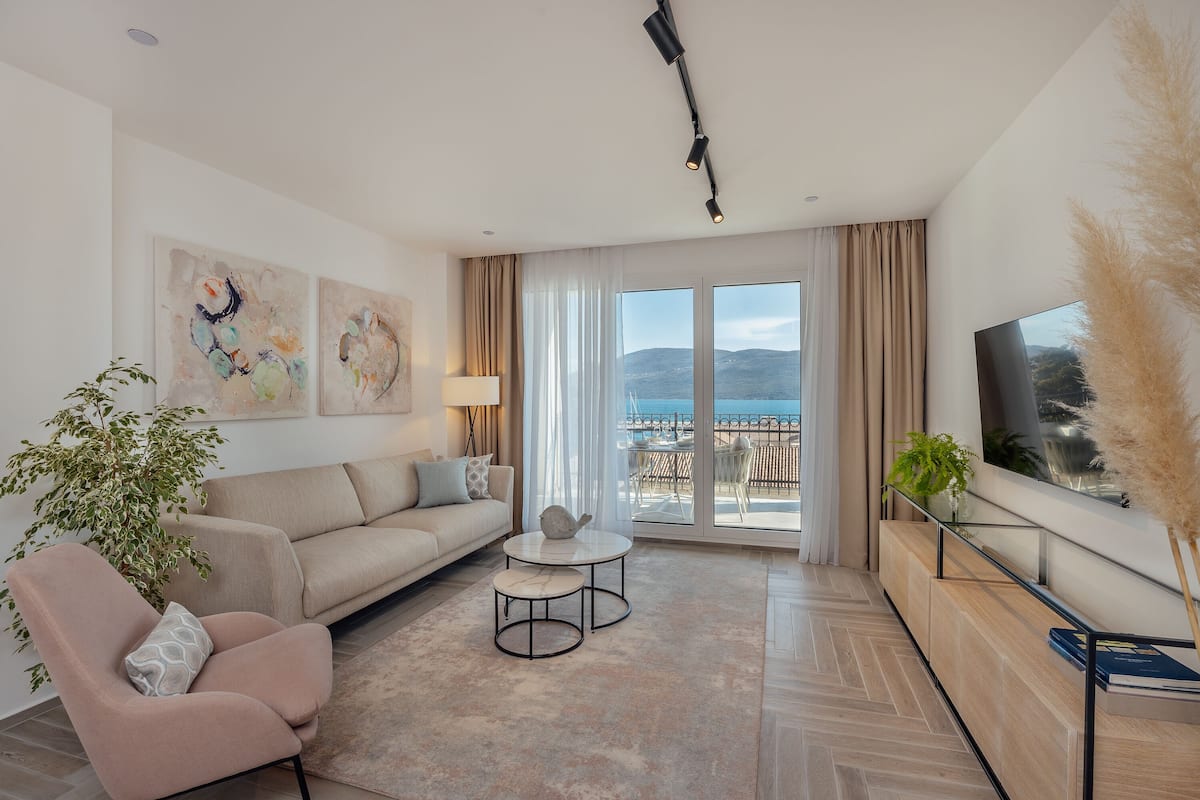 Ein modernes Wohnzimmer mit Sofa, Ohrensessel, Couchtisch und Kunstwerk an der Wand.