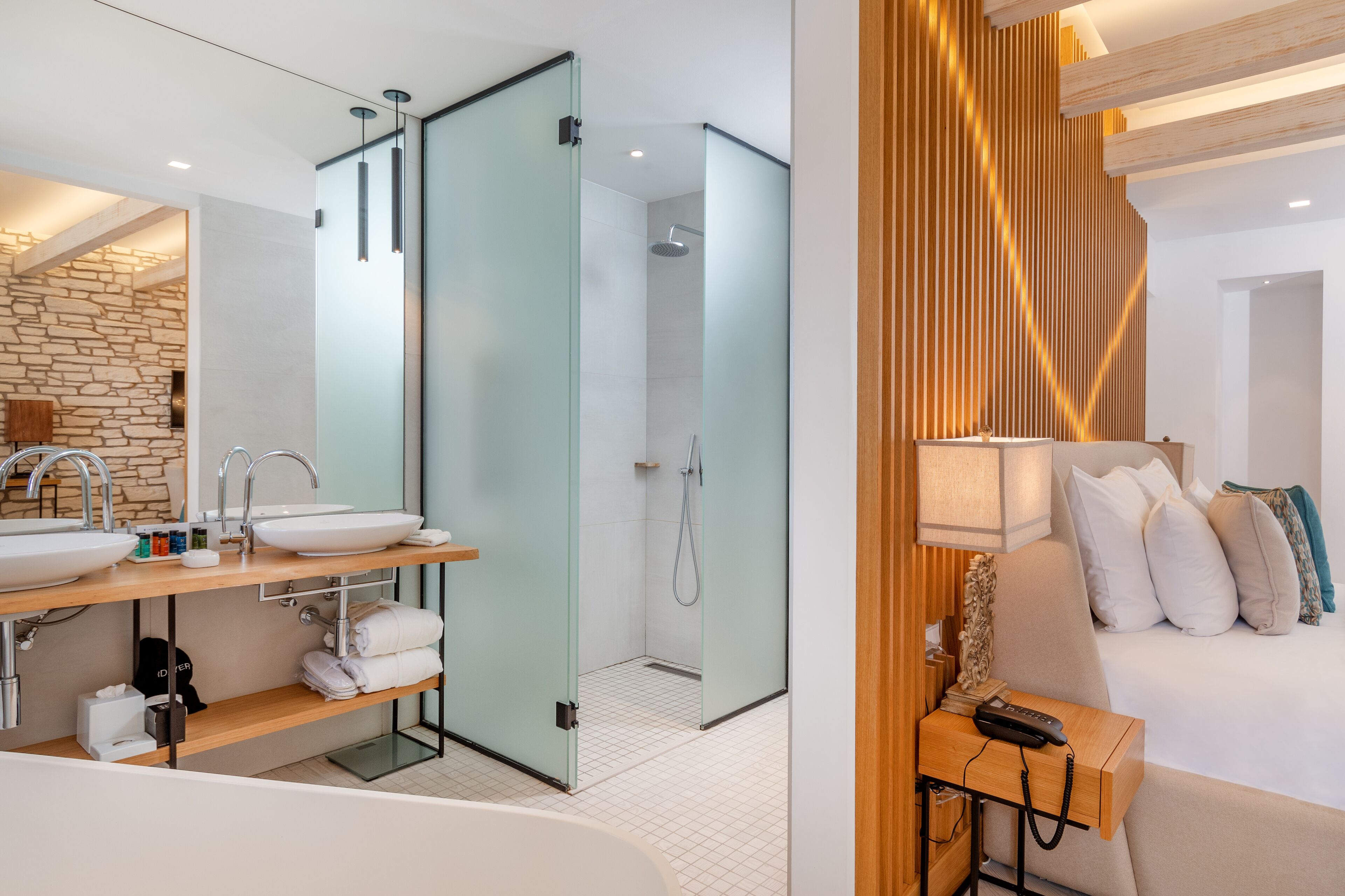 A modern bathroom with a double sink, glass shower enclosure, and a wooden accent wall.