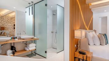 A modern bathroom with a double sink, glass shower enclosure, and a wooden accent wall.