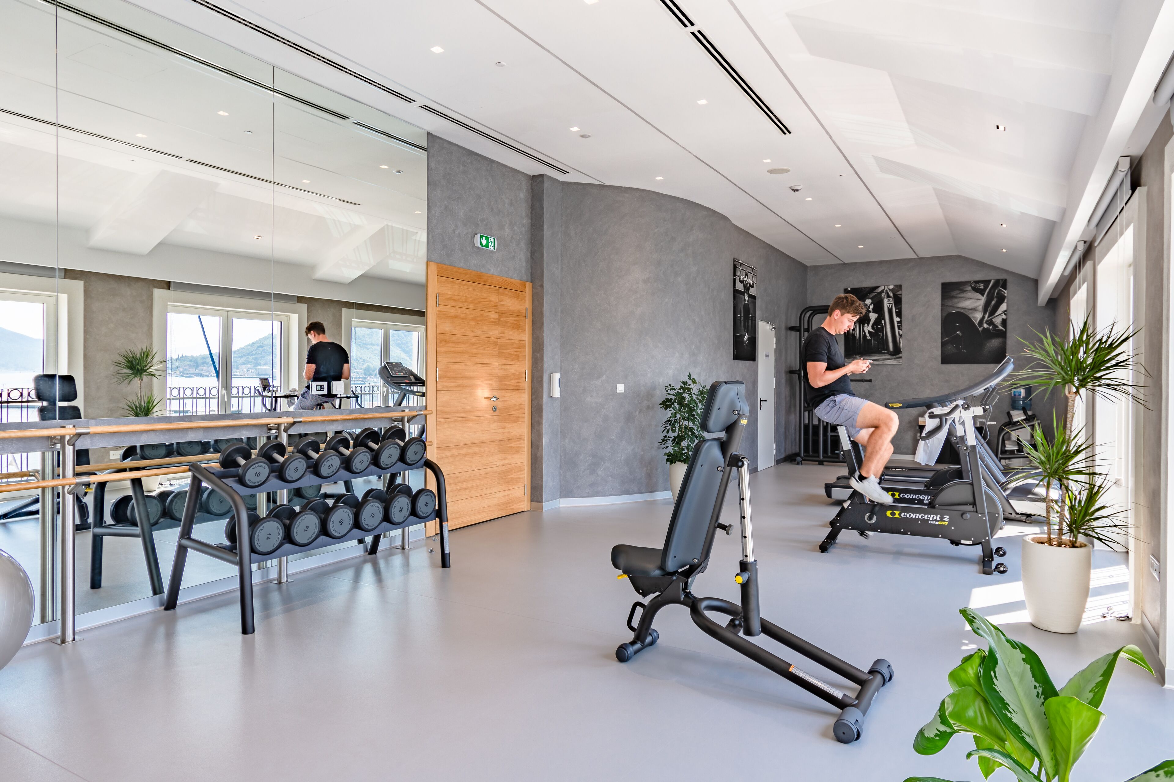 Un gimnasio moderno con equipo de ejercicio, una puerta de madera y ventanas amplias.