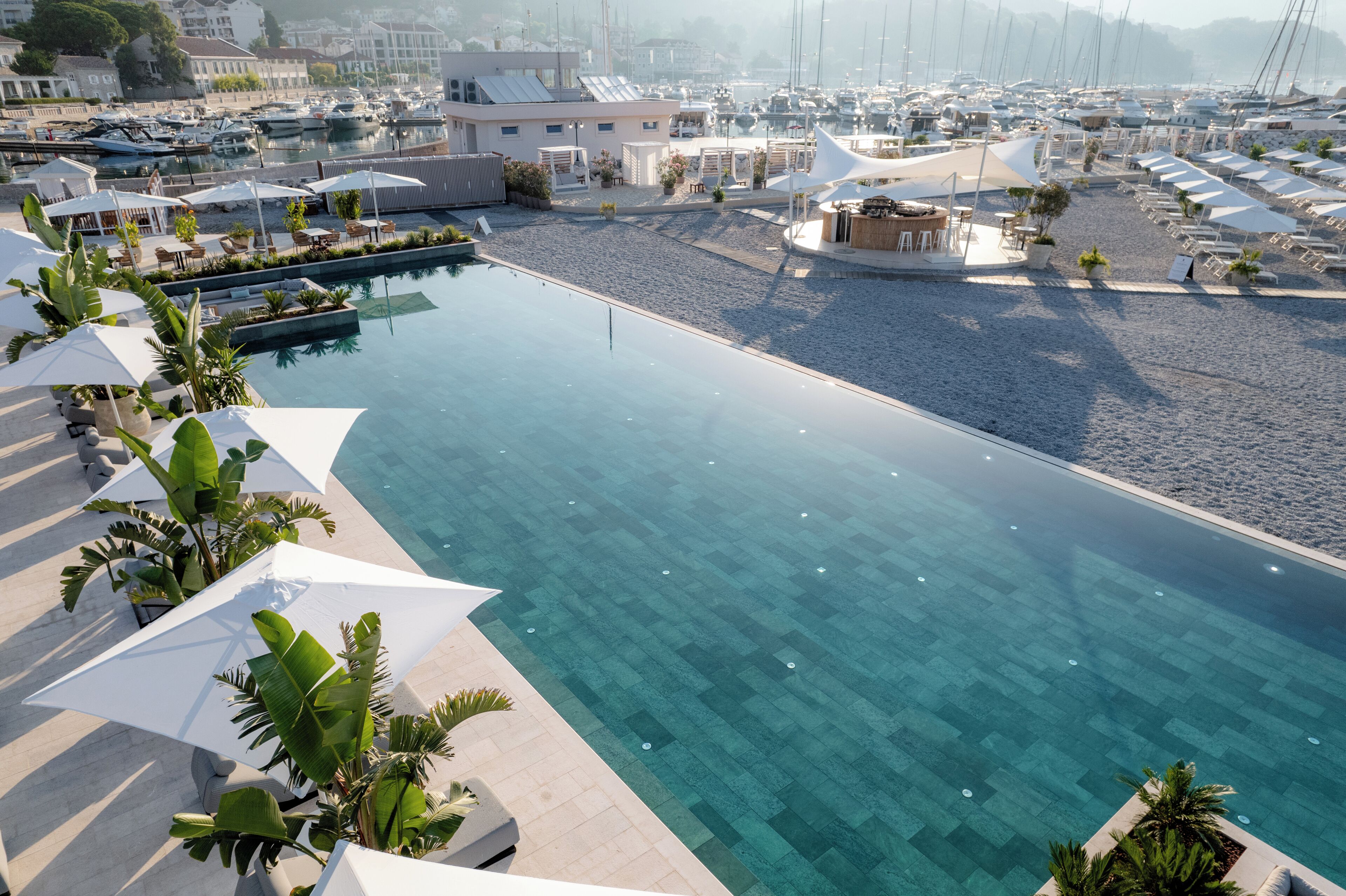 Un puerto deportivo con barcos, piscina y zonas de estar al aire libre.