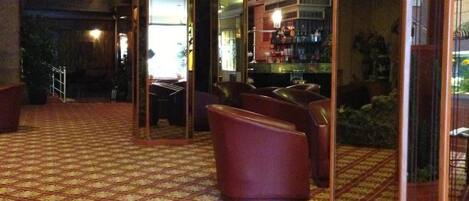 A hotel lobby with a patterned carpet, seating area, and a bar.